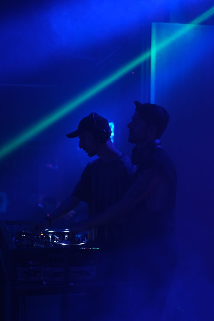 men with headphones standing beside a sound mixer