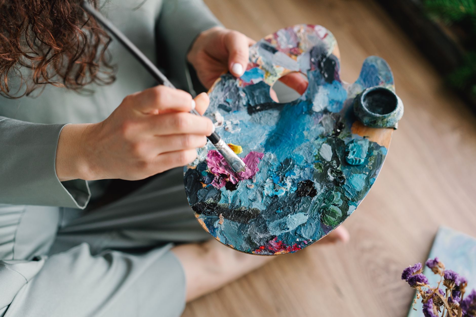 a person holding a brush and palette with colorful paint