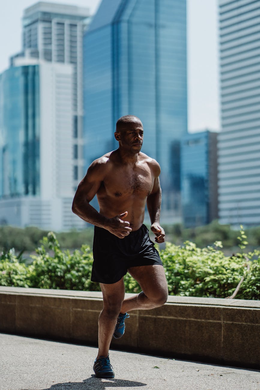 shirtless man in black shorts running in the street