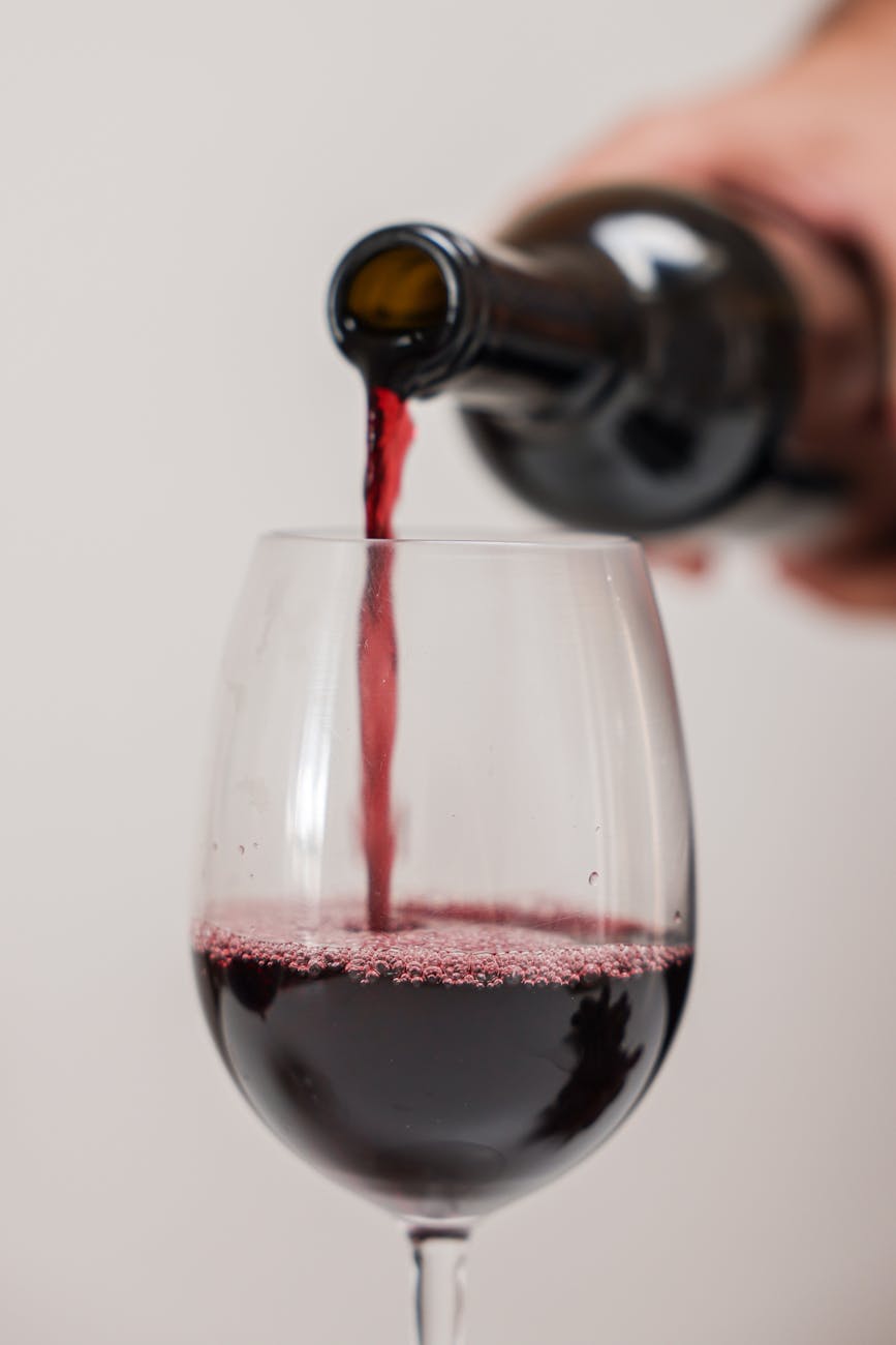 a person pouring wine on a clear glass